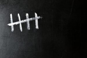 Five chalk tally marks on a black chalkboard background.